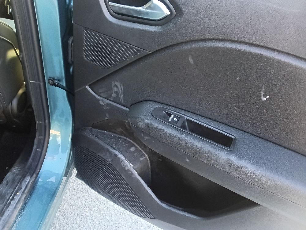 Interior door panel with shallow white dust and smudges on the black plastic — the kind that wipes off with a damp cloth.
